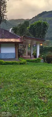 a building in a field of green grass with a yard at Munnar home stay in Munnar