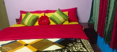 a bed with yellow and red pillows and red peppers at Munnar home stay in Munnar