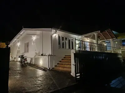 a white house with a motorcycle parked in front of it at Abbu Royal Palace Cottage in Ooty