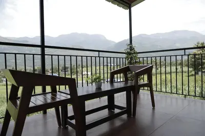 a table and two chairs on a balcony with a view at Le Sancta homestay in Marayoor