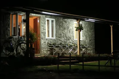 a stone house with a bench in front of it at night at Wild and Free Farm Stay in Ooty
