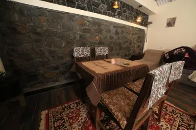 a small table and chairs in a room with a brick wall at Wild and Free Farm Stay in Ooty