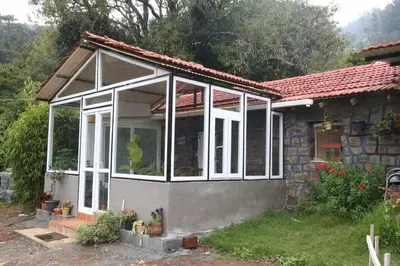 a house with a large screened in porch at Wild and Free Farm Stay in Ooty