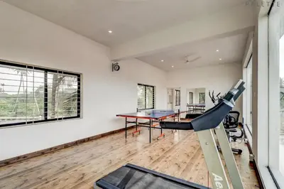 a room with a gym with a table and a treadmill at Heritage Shelters Resort in Mysore