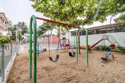 a playground with a swing set in the sand at Heritage Shelters Resort in Mysore