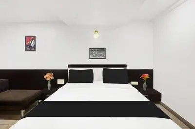 a bedroom with a black and white bed and a couch at Super Townhouse City Center Near Mysore Palace Formerly Aavass Inn in Mysore