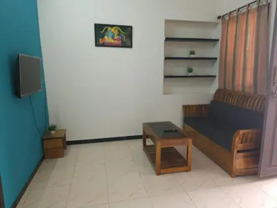 a living room with a couch and a tv at SHIs Spandha Apartments Near Coimbatore Airport in Coimbatore