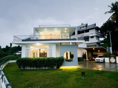 a large white house with a yard at Rosy Villa - Riverside Stay with Pool & View in Alwaye