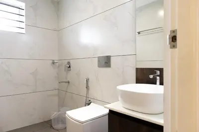 a white bathroom with a sink and a toilet at Rosy Villa - Riverside Stay with Pool & View in Alwaye