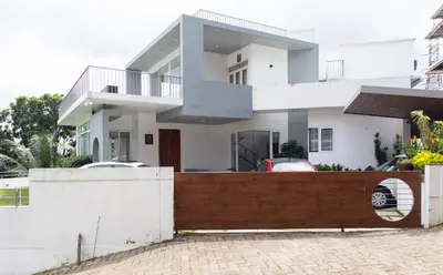 a house with a wooden fence in front of it at Rosy Villa - Riverside Stay with Pool & View in Alwaye