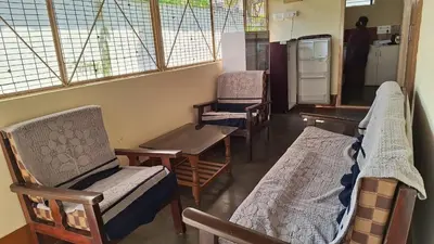 a room with chairs and a table and a refrigerator at Golden Nest Home Stay in Mysore