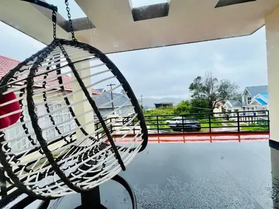 a hammock on a balcony with a view of a yard at Teyt's Green Haven - 3 BHK in Ooty