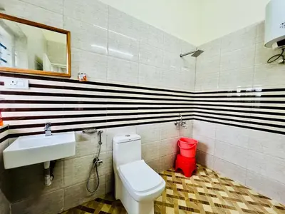 a bathroom with a white toilet and a sink at Teyt's Green Haven - 3 BHK in Ooty