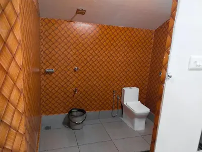 a bathroom with a toilet and a trash can at Bamboo Suite at Merlys Fruit Garden in Kotamangalam