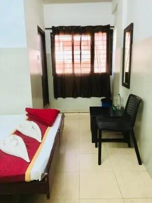 a bedroom with a bed and a desk and a window at Midtown Residency in Kozhikode