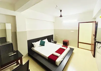 a bedroom with a bed and a desk and a mirror at Midtown Residency in Kozhikode