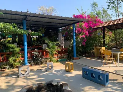 a patio with a table and chairs and flowers at Wilderness Jungle Camp in Malavalli