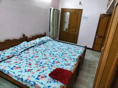 a bedroom with a bed with a blue comforter at Honeycomb Homestay Ground Floor in Palani