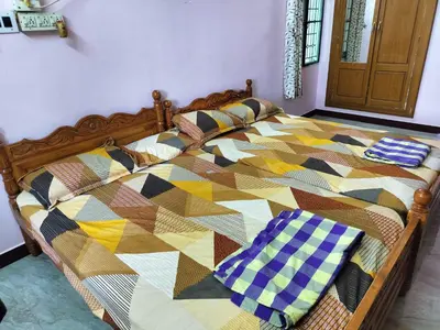 a bed with a colorful quilt on top of it at Honeycomb Homestay Ground Floor in Palani