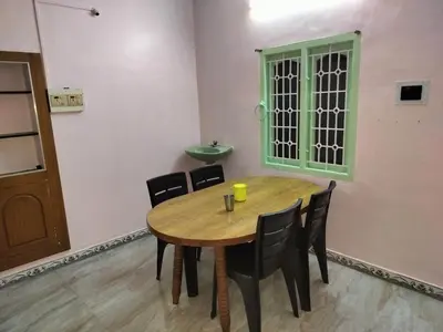 a dining room with a wooden table and chairs at Honeycomb Homestay Ground Floor in Palani