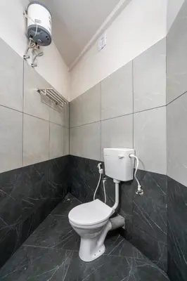 a bathroom with a toilet and a light on the wall at Amala Arcade AC Rooms in Trichūr