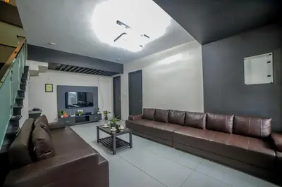 a living room with a brown couch and a tv at Abhinav Nest by Xplore Indo in Kodanād