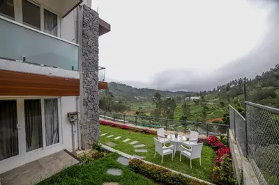 a balcony with a table and chairs and a view at Abhinav Nest by Xplore Indo in Kodanād