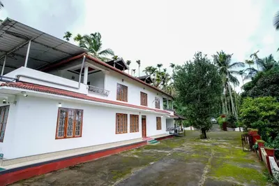 a white building with a lot of windows at Wayanad Palm Grove Retreat 1st Floor in Wayanad