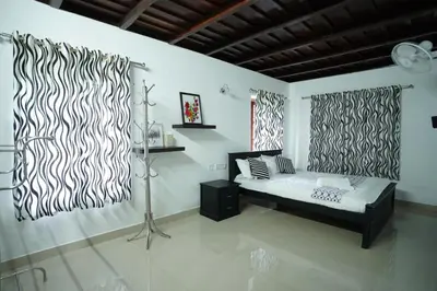 a bedroom with black and white curtains and a bed at Wayanad Palm Grove Retreat 1st Floor in Wayanad