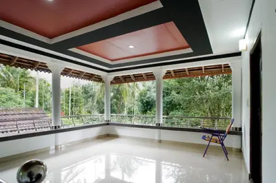 a room with a balcony with a chair and windows at Wayanad Palm Grove Retreat 1st Floor in Wayanad