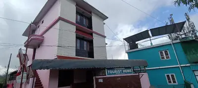 a building next to a building with a sign on it at Swarna Tourist home Munnar in Munnar