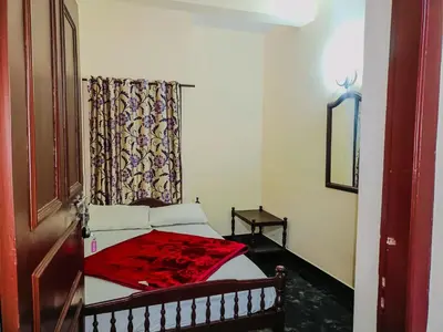 a small bedroom with a bed with a red blanket at Swarna Tourist home Munnar in Munnar