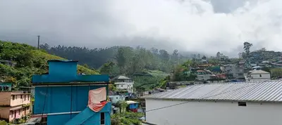 a city with a blue building and a mountain at Swarna Tourist home Munnar in Munnar