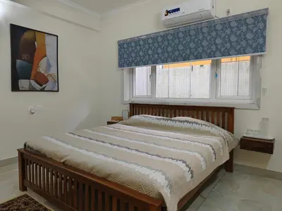 a bedroom with a bed and a window with a air conditioner at 7 Elysee Homestay - Lapis - Premium 3BHK Family Flat in Trichūr