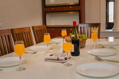 a table with glasses of orange juice and a bottle of wine at Puzhayoram holiday home, Aluva in Alwaye