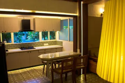 a kitchen with a table and chairs and a yellow curtain at River Wild holiday home in Athirappilly