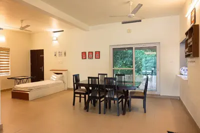 a dining room with a table and chairs and a couch at Theeram Riverside Holiday Home in Māla