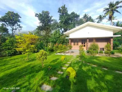 a house in a field with a grass yard at Merlys Fruit Garden in Cochin