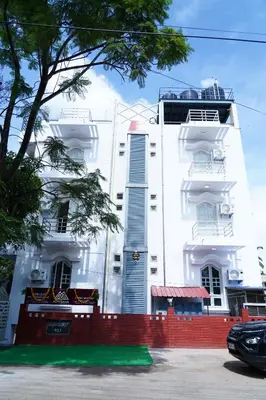 a white building with a red fence in front of it at Meridian Rooms and Service Apartment in Mysore