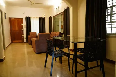 a living room with a glass table and chairs at Meridian Rooms and Service Apartment in Mysore
