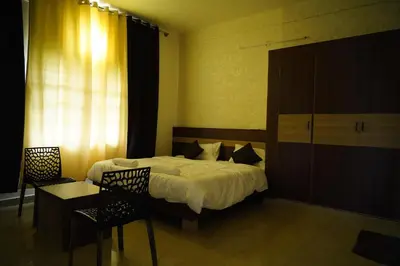 a bedroom with a bed and a table and chairs at Meridian Rooms and Service Apartment in Mysore