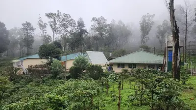 a house with a green roof in a field at Ibex Resorts, Valparai Mistly in Vālpārai