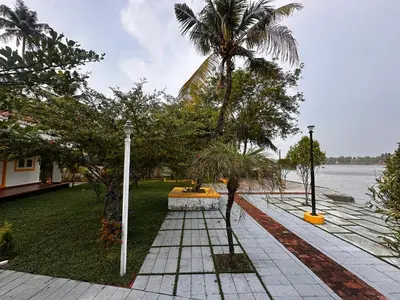 a garden with palm trees next to a body of water at CASA DE CANOLI - A Private backwater villa in Kodungallūr