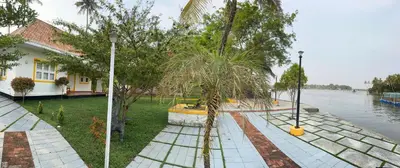 a house by the water with trees in the yard at CASA DE CANOLI - A Private backwater villa in Kodungallūr