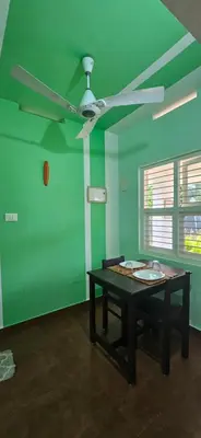 a green room with a table and a ceiling fan at CASA DE CANOLI - A Private backwater villa in Kodungallūr