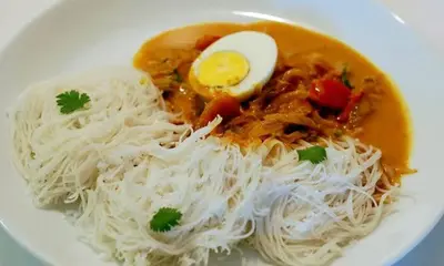 a plate of food with noodles and an egg on it at CASA DE CANOLI - A Private backwater villa in Kodungallūr
