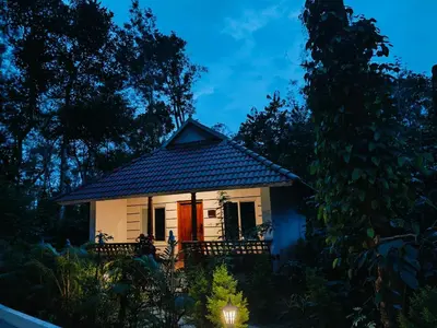 a small white house with a dark roof at Coorg Orange Blossom Resort and Spa in Suntikoppa
