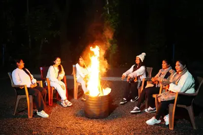 a group of people sitting around a fire pit at Coorg Orange Blossom Resort and Spa in Suntikoppa
