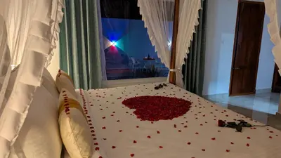 a bed with a pile of red hearts on it at Coorg Orange Blossom Resort and Spa in Suntikoppa