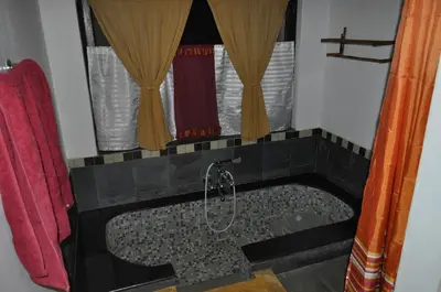 a bathroom with a bath tub with a shower at O'Land Wilderness Lodge in Kolakambe